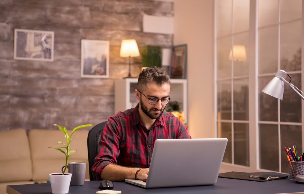 A man is doing something on the Internet while sitting at a laptop