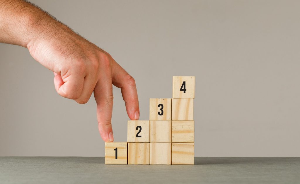 A man's hand climbs the steps of small blocks